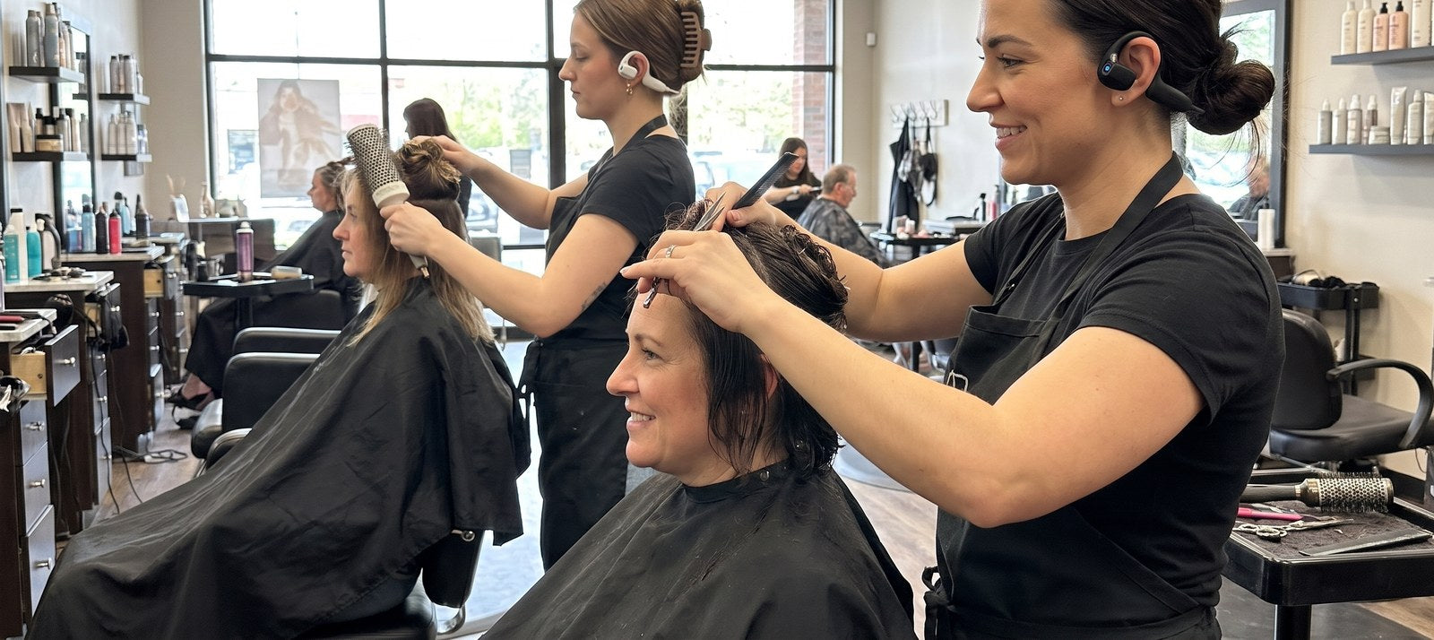 Two stylists each wearing a ChairClips headset